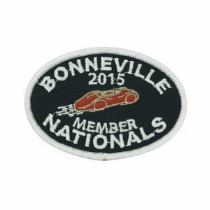 May include: Oval patch with white stitching and a black background. The patch features the words "BONNEVILLE 2015 MEMBER NATIONALS" in white, with a red race car graphic in the center. A collectible item.