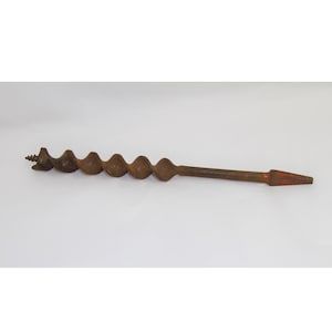 May include: A rusty metal drill bit with a red tip. The drill bit is about 12 inches long and has a spiral design.