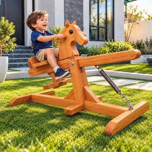 May include: A wooden rocking horse seesaw with a natural brown finish, featuring a horse-shaped head, a seat, footrests, and a metal spring mechanism attached to the base. The structure is made of smooth wood planks and sits on a wide frame.