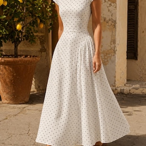 May include: A white midi-length dress featuring a black polka dot pattern, a high round neckline, short cap sleeves, and a fitted bodice that transitions into a flared, pleated skirt. The garment is constructed with a defined waistline.