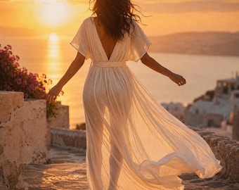 May include: A floor-length white dress with short flutter sleeves, a deep V-neckline, and a cinched waist. The garment features a lightweight, semi-sheer fabric that flows into a full, loose skirt, creating a soft silhouette against the light.