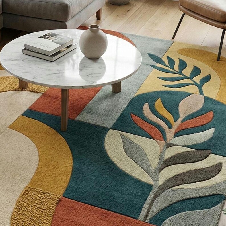 Modern abstract hand-tufted rug with geometric shapes and leaf pattern in teal, mustard, rust, and neutral tones placed in a stylish living room.