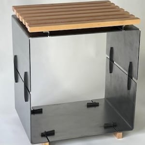 Puede incluir: Una mesa auxiliar cuadrada y moderna con estructura de acero inoxidable y tapa de madera con listones. La mesa se apoya en pequeños bloques de madera en la base y presenta cierres negros. El diseño es minimalista e industrial.