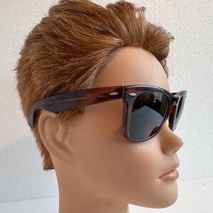 May include: Dark brown tortoiseshell sunglasses with square frames and dark lenses. The image shows the sunglasses on a mannequin head with brown hair.
