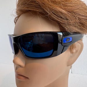 May include: Black sunglasses with blue lenses. The frames are glossy black with a blue accent on the temples. The lenses reflect the surrounding environment. Sport sunglasses.