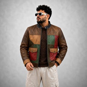 May include: A multi-colored leather jacket featuring brown, green, and red panels with a stand-up collar, a front zipper closure, and two flap pockets. The jacket is worn over a dark brown textured sweater and light-colored cargo pants.