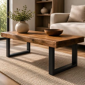Pode incluir: Uma mesa de centro retangular com tampo de madeira escura e pernas de metal preto. Uma tigela de madeira e um vaso bege com vegetação estão sobre a mesa. A mesa está sobre um tapete bege.