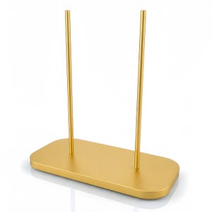 May include: A gold-colored metal display stand featuring a rectangular base with rounded corners and two vertical, parallel rods extending upward from the surface. The stand has a smooth, matte finish and a simple, functional design.