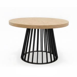 Op de afbeelding: Een ronde tafel met een licht eikenhouten blad en een zwart metalen onderstel. De basis heeft verticale zwarte staven die naar beneden taps toelopen, wat een modern ontwerp creëert. De tafel is geschikt voor diverse interieurs. Diameter: ongeveer 90 cm.