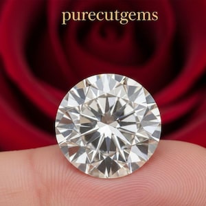 May include: A large, round, brilliant-cut diamond with many facets, reflecting light. The diamond is held against a red background, with the text "purecutgems" in gold at the top. The gem is a symbol of luxury and elegance.