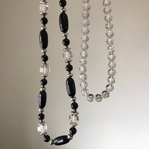 May include: Two necklaces, one with black and silver beads and the other with clear glass beads.