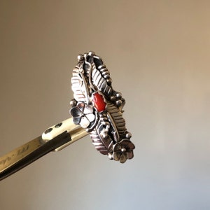 大きなスターリングシルバーの南西部ナバホ族のリング。花、葉、つるのディテールで囲まれ、小さな爪付きコーラル、US リングサイズ 7.5