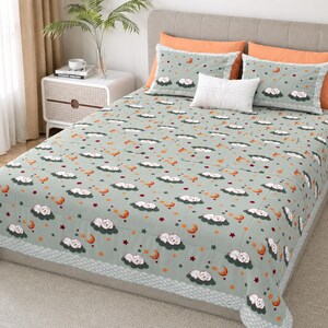 May include: A light green bedspread featuring a repeating pattern of white sleeping cats on dark green clouds, orange crescent moons, and small red stars. The set includes two matching pillowcases and a solid white rectangular throw pillow.