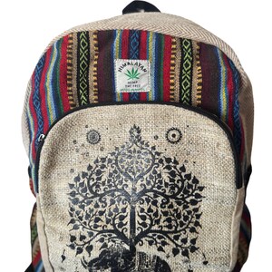 Puede incluir: Mochila de cáñamo beige con un diseño de elefante y árbol negro. La sección superior presenta un patrón de rayas de colores. La mochila tiene un bolsillo frontal con cremallera y una pequeña etiqueta que dice "Himalayan Hemp THC Free Made in Nepal."