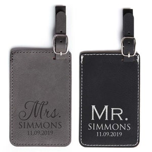 A personalized Mr. and Mrs. Luggage tag set is shown.  The leather luggage tags are gray and black.  Luggage tags are gifts for a couple.  Each luggage tag is personalized with Mr or Mrs, the couple's last name, and the wedding date.