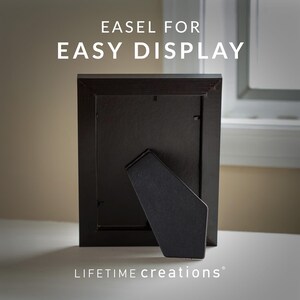 May include: A black picture frame with an easel back for display. The frame is rectangular and made of dark wood. The text "EASEL FOR EASY DISPLAY" is at the top, and "LIFETIME creations" is at the bottom.