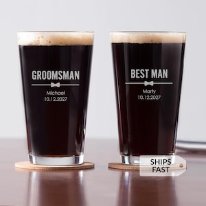 May include: Two pint glasses filled with dark beer and foam, each on a cork coaster. One glass says "Groomsman" with a bow tie graphic, the name "Michael" and date "10.12.2027". The other says "Best Man" with "Marty" and "10.12.2027".