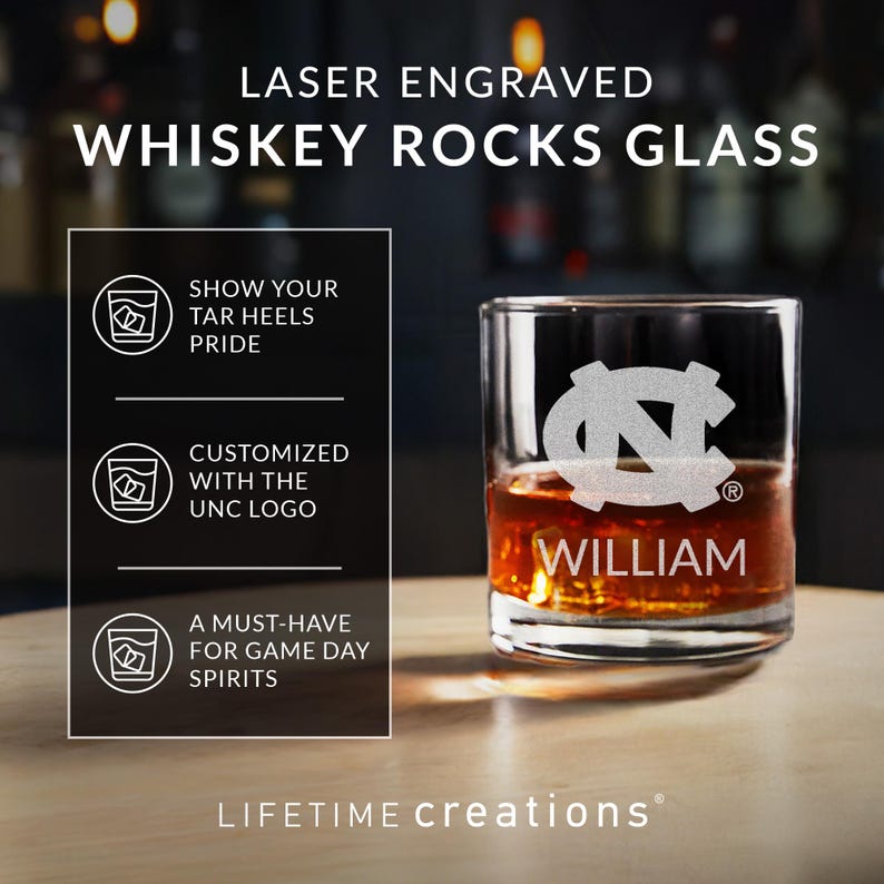 May include: A clear whiskey rocks glass with a laser-engraved UNC logo and the name "WILLIAM." The glass is filled with amber liquid. Text on the glass reads "LASER ENGRAVED WHISKEY ROCKS GLASS."