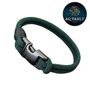 Puede incluir: Una pulsera de cuerda verde oscuro con un cierre plateado. La pulsera está hecha de una cuerda gruesa y tejida. El cierre tiene un diseño simple y seguro. Un accesorio elegante para el uso diario.