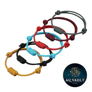 Op de afbeelding: Een verzameling kleurrijke touwarmbanden. De armbanden zijn er in verschillende kleuren, waaronder geel, zwart, blauw, rood en grijs. Elke armband heeft een geknoopt ontwerp en is verstelbaar. De afbeelding bevat ook een rond logo met de tekst "AQ VAULT LIMITED".