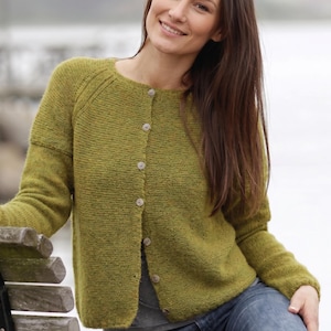 May include: A long-sleeved, olive green knit cardigan featuring a round neckline and a front button closure with six light-colored, circular buttons. The garment has a textured, slightly heathered appearance with ribbed detailing along the shoulders.