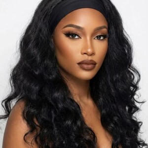 Peut inclure: Une femme à la peau foncée avec de longs cheveux noirs ondulés. Elle porte un bandeau noir et a un maquillage des yeux foncé et du rouge à lèvres marron. Le fond est blanc uni.