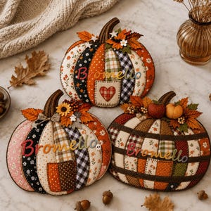 Puede incluir: Tres decoraciones de calabaza de tela con diseños de patchwork en patrones naranja, negro, blanco y marrón. Cada calabaza está adornada con hojas de otoño, bayas y el nombre Bromello en letras cursivas de colores. Una calabaza incluye un parche de corazón.