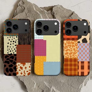 Peut inclure: Trois coques de téléphone colorées avec des motifs patchwork. Chaque coque présente un motif différent, notamment des imprimés animaliers, des carreaux et des formes géométriques. Les coques sont disposées sur une surface grise texturée.