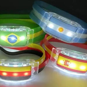 Può includere: Una collezione di braccialetti LED luminosi con le bandiere di Brasile, Argentina, Spagna e Germania. I braccialetti sono realizzati in materiale flessibile e hanno un alloggiamento luminoso in plastica trasparente. Le luci sono luminose e colorate.
