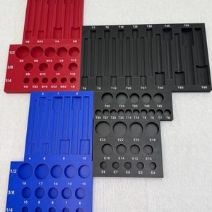 May include: A collection of red, blue, and black tool organizers featuring various circular and rectangular slots. Each organizer is labeled with specific sizes including fractions like 1/2, 3/8, 1/4, and alphanumeric codes such as T7, T60, E24, and E4.