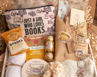 Puede incluir: Una caja de regalo con una bolsa de cosméticos con el texto "JUST A GIRL WHO LOVES BOOKS", una bolsa de Border Golden Oat Crumbles, sales de baño Epsom y un posavasos con el texto "THERE IS NO SUCH THING AS TOO MANY BS".