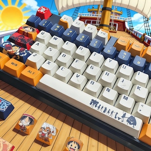May include: A custom mechanical keyboard with white, blue, and orange keycaps. The keycaps feature cartoon character designs and symbols. The keyboard is set against a backdrop of a ship and a sunny sky.