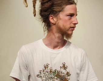May include: A man with long brown dreadlocks is wearing a white t-shirt with a green, brown, and red graphic of a lichen. The text "I like lichen" is printed below the graphic.