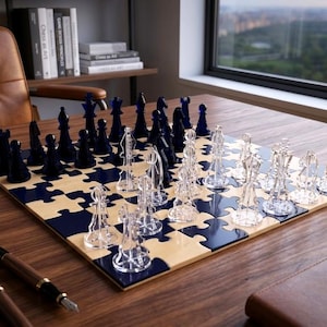 Puede incluir: Un juego de ajedrez moderno con un tablero de madera tipo rompecabezas y piezas transparentes y azul marino. Las piezas de ajedrez están dispuestas en el tablero, listas para jugar. El tablero está sobre un escritorio de madera con bolígrafos y un cuaderno.