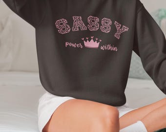 Sudadera Sassy de cuello redondo, detalle de corona en tonos pastel, comodidad acogedora.