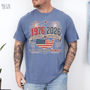 A man wearing a blue t-shirt with a graphic design celebrating the 1976-2026 Centennial Semicentennial of the United States.