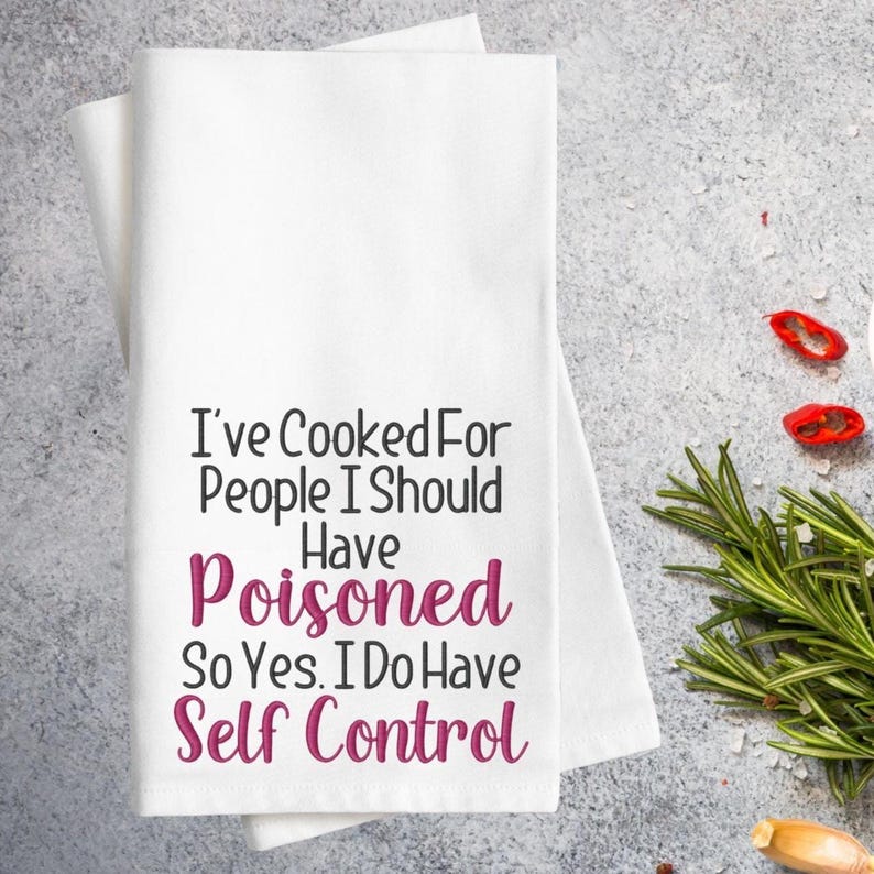 Puede incluir: Pa&ntilde;o de cocina blanco con el texto "I've Cooked For People I Should Have Poisoned So Yes. I Do Have Self Control" en letras negras y rosas. La toalla est&aacute; doblada y colocada sobre una superficie gris.