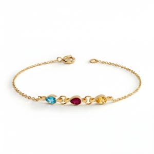 May include: A gold chain bracelet featuring three pear-shaped gemstones in a row. The stones are a light blue topaz, a deep red ruby, and a bright yellow citrine, each set in a gold bezel. The bracelet includes a circular spring ring clasp.