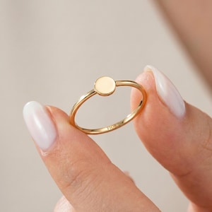 Peut inclure: Une bague en or dotée d'un anneau fin et poli, surmontée d'un petit disque circulaire plat. L'intérieur de l'anneau porte une gravure claire avec le texte FIOR, visible au centre de la circonférence intérieure de la bague.