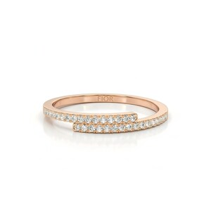 May include: Rose gold ring with a distinctive open design. The ring is adorned with a band of small, sparkling diamonds. The word "FIOR" is engraved on the ring. A modern and elegant piece of jewellery.