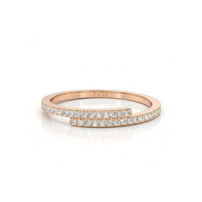 May include: Rose gold ring with a distinctive open design. The ring is adorned with a band of small, sparkling diamonds. The word "FIOR" is engraved on the ring. A modern and elegant piece of jewellery.