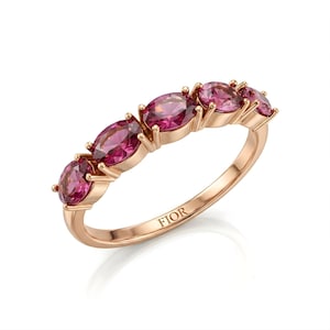 Op de afbeelding: Ros&eacute;gouden ring met vijf ovale roze edelstenen. De ring heeft een delicate band en het woord "FIOR" is aan de binnenkant gegraveerd. De edelstenen zijn gezet in een klauwzetting.