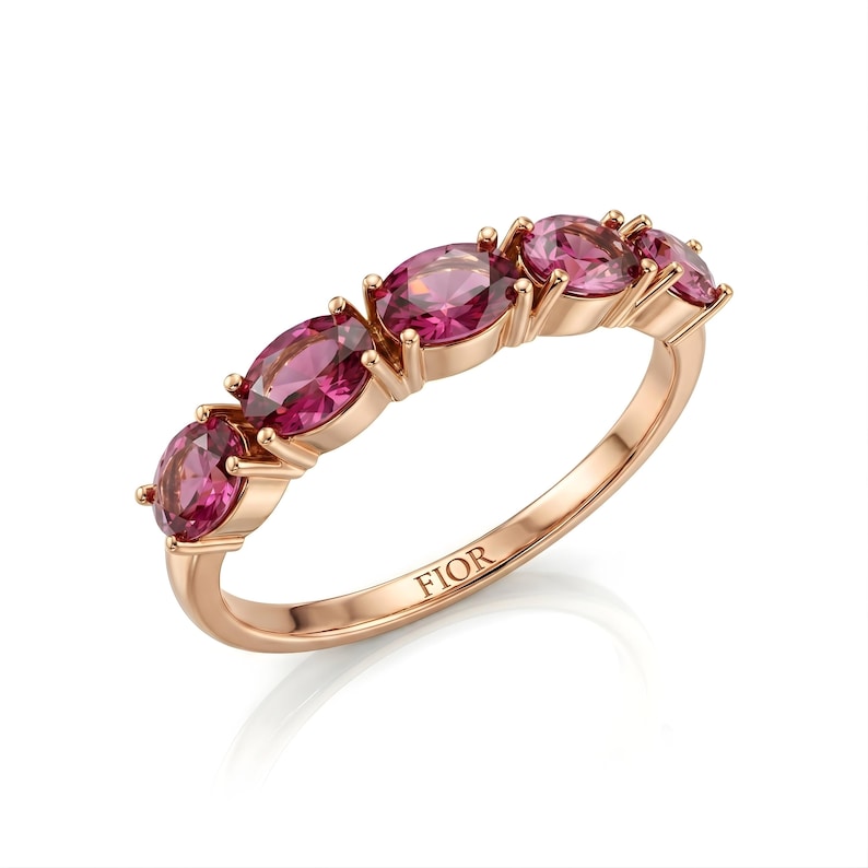 Op de afbeelding: Ros&eacute;gouden ring met vijf ovale roze edelstenen. De ring heeft een delicate band en het woord "FIOR" is aan de binnenkant gegraveerd. De edelstenen zijn gezet in een klauwzetting.
