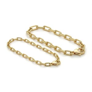 May include: Two gold-colored chain link bracelets. One bracelet is larger than the other. Both bracelets have a lobster claw clasp. The bracelets are displayed on a white background.