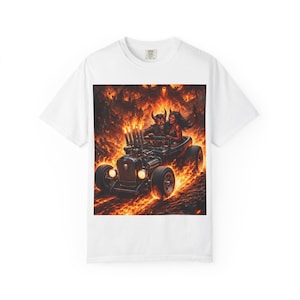 Puede incluir: Camiseta blanca con un llamativo gráfico de un hot rod conducido por dos figuras diabólicas en un paisaje de fuego. La obra de arte muestra un coche antiguo con llamas y un fondo infernal, creando un diseño audaz y llamativo.