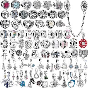 Könnte beinhalten: Eine Sammlung von silberfarbenen Charm-Beads und Anhängern. Designs umfassen Herzen, Blumen, Sterne und Charms zum Thema Reisen. Einige Charms haben farbige Akzente, und eine Sicherheitskette ist enthalten.