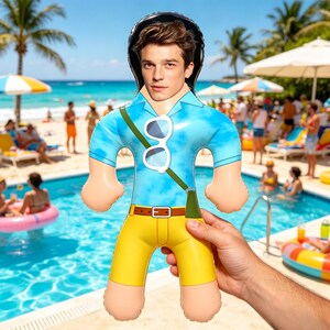 May include: An inflatable doll with a male face, wearing a blue shirt, yellow shorts, and sunglasses. The doll has a black hat and a green strap. The background shows a pool, beach, and people.