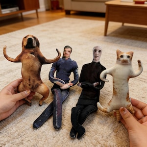 May include: Four plush dolls: a dog, a man in a blue shirt and jeans, a man in a black shirt and pants, and a cat. The dog is brown and tan, the cat is white and orange. The men are seated, the dog and cat are standing with arms raised.