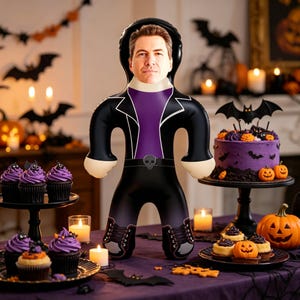 May include: A custom plush doll featuring a printed photograph of a man's face on a cartoon-style body. The doll wears a black jacket with a purple shirt, a belt with a skull buckle, and black boots with laces, all rendered in a flat graphic design.