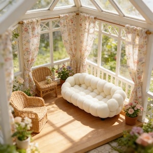 May include: Miniature dollhouse interior with a white sofa, two wicker chairs, and floral curtains. The room has a wooden floor and is filled with potted plants. The windows offer a view of a garden.